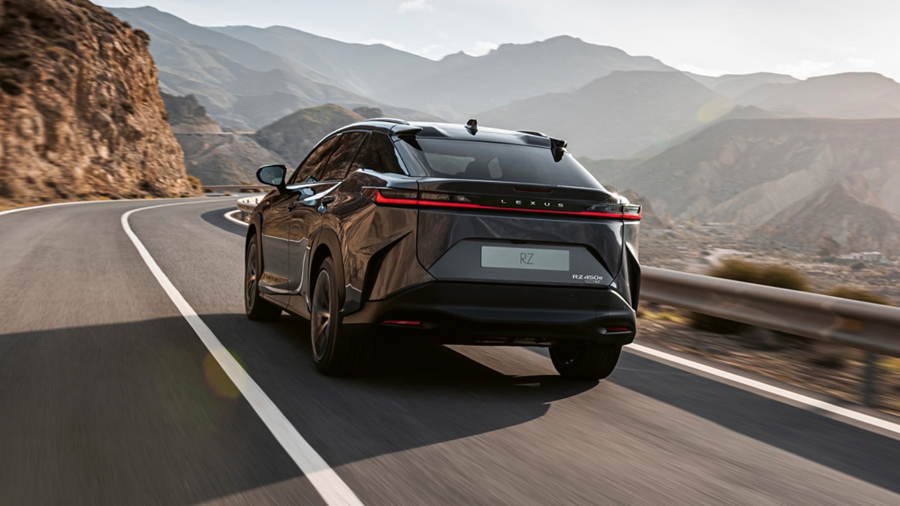 Rear view of the Lexus RZ 450e driving in a mountainous location